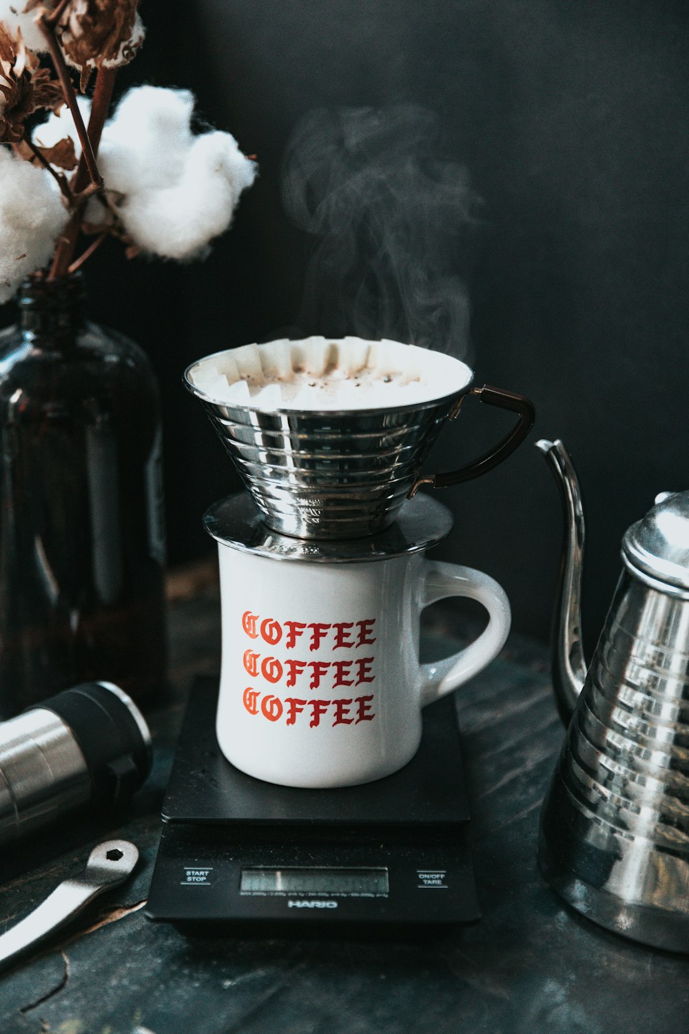 Gotero de café con una taza y utensilios sobre una mesa