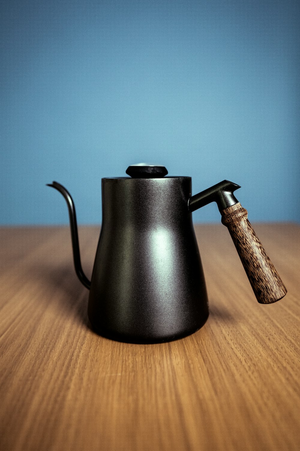 Hervidor negro de cuello de cisne sobre una mesa de madera